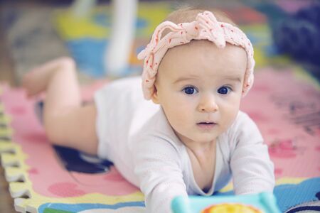 A cute young baby playing inside home with colorful toysの写真素材