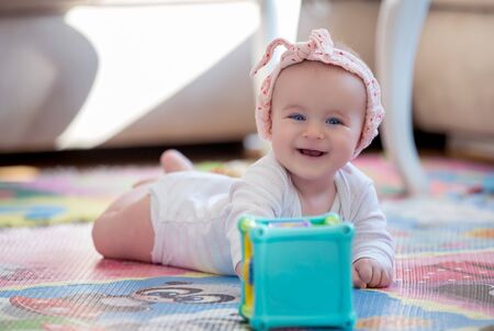 A cute young baby playing inside home with colorful toysの写真素材