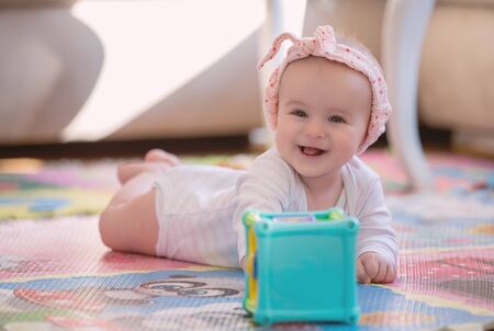 A cute young baby playing inside home with colorful toysの写真素材