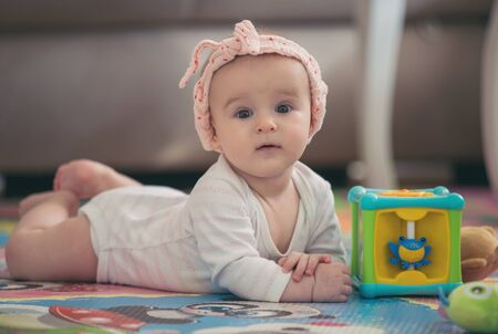 A cute young baby playing inside home with colorful toysの写真素材