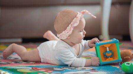 A cute young baby playing inside home with colorful toysの写真素材