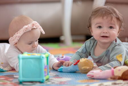 cute twins, baby girl and baby boy playing with toys by the homeの写真素材