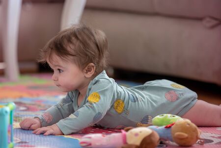 A cute young baby playing inside home with colorful toysの写真素材