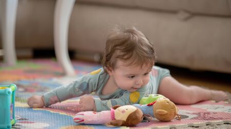A cute young baby playing inside home with colorful toysの写真素材