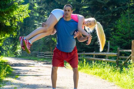 Young sports couple doing exercises in forestの写真素材