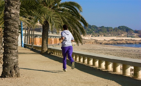 Girl in sports clothes running down the path along the seaの写真素材