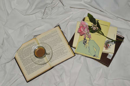 Cup of coffee with books and a rose in bedの写真素材