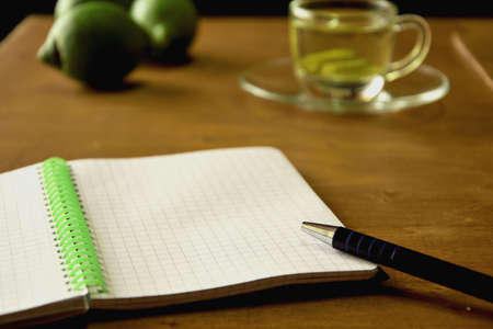 Notepad, a glass of lemon tea and lemons on wooden surfaceの写真素材