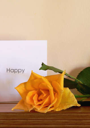 Yellow roses and a "Happy" White card (on wooden Surface)の写真素材