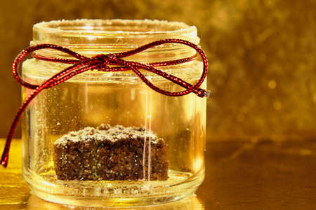 Golden magic winter - a jar with cake inside, red bow, golden background and snowの写真素材