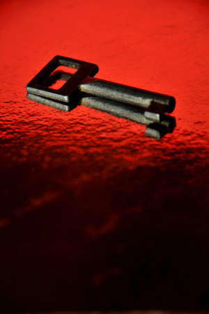 Iron key on a red black surfaceの写真素材