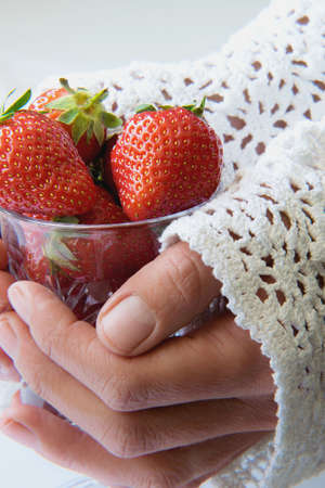 Hands holding glass of strawberriesの写真素材