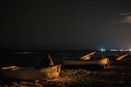 Man in boat looks at the starry sky