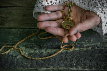 Old fashion lady holds a golden key in her handsのeditorial素材
