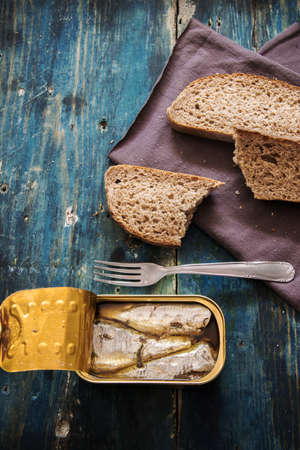 Top view of homemade whole grain bread and canned fish on the rustic tableの写真素材
