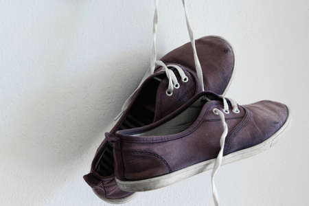 A pair of old sports shoes hanging on the wallの写真素材