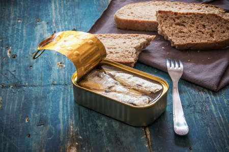 Sardines in the can and slices of bread on blue wooden tableの写真素材