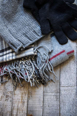 Detail of winter woolen accessory - hat, gloves and scarf on wooden background. Cozy autumn-winter conceptの写真素材