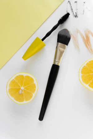 Top view of modern fashion flat lay, fashion workspace with cosmetics and fresh lemons on white...