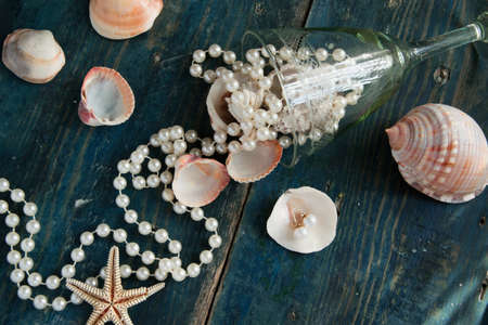 The pirate's treasure - white pearls and shells on blue wooden background, vintage fashion conceptの写真素材