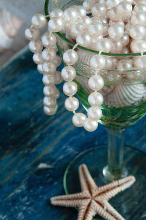 The pirate's treasure - white pearls and shells on blue wooden background, vintage fashion conceptの写真素材