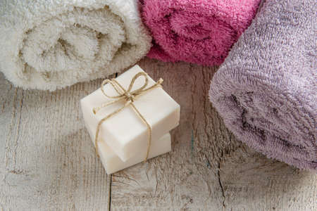Spa set products - two soap bars, soft towels and sea shells on wooden background with space for textの写真素材