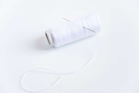 White thread and sewing needle on white background with space for text. Minimal sewing toolsの写真素材