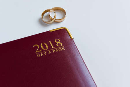 Planning a wedding in 2018. Top view of 2018 personal organizer and two wedding rings on white background with space for text. New life conceptの写真素材