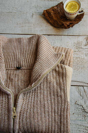 Cozy warm knitted sweaters and cup of tea on wooden background with space for text. Concepts - fashion, comfortable time spent at home, rustic hygge life, relaxingの写真素材