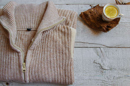 Cozy warm knitted sweaters and cup of tea on wooden background with space for text. Concepts - fashion, comfortable time spent at home, rustic hygge life, relaxingの写真素材