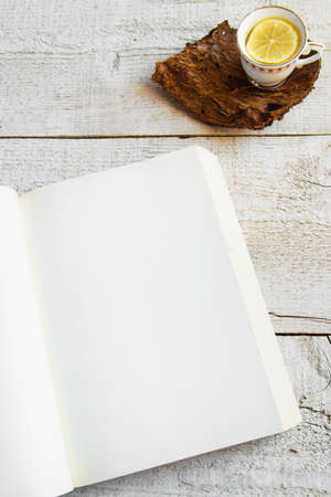 Cup of tea and book on wooden background with space for text. Concepts - relaxing time spent at home, rustic hygge life, studyingの写真素材