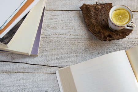 Cup of tea and books on wooden background with space for text. Concepts - relaxing time spent at home, rustic hygge life, studyingの写真素材