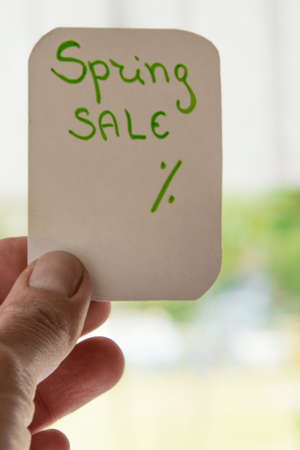 Woman hand holding a message card for spring sale
