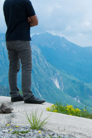 Young adult man is watching the awesome mountains peak by the topの写真素材