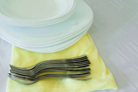 Fresh white and yellow tableware set: napkins,plates and silver utensils