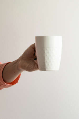 Isolated crop view of woman hand holding a white mug, white background with space for text