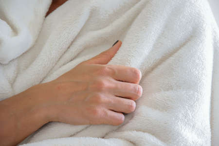 Front close up view of a woman wrapped in a warm white blanket