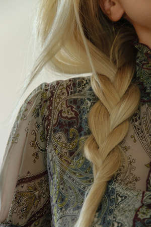 Concept of stylish hairstyle. Close-up of a blond woman with braid hair. Elegant everyday hairstyle