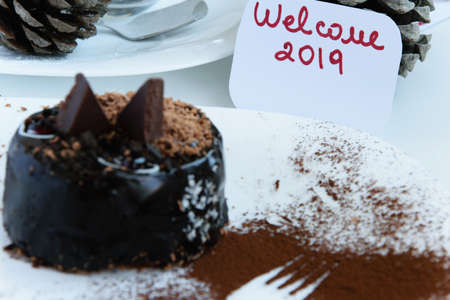 Delicious winter chocolate cake in a plate, a fork outline cacao decoration and a greeting card...