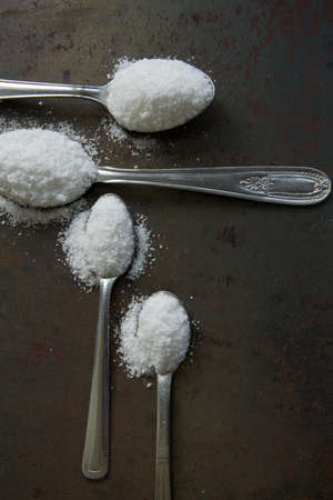 Four spoons with sea salt on rustic background