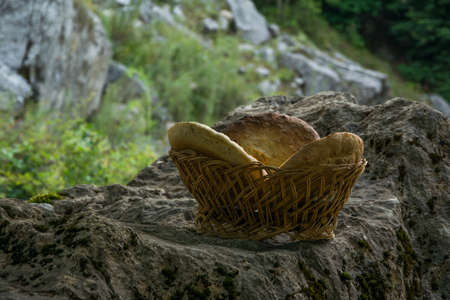 Traditional unleavened homemade bread in wooden basket on the rock in high mountainの写真素材