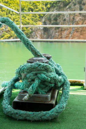 Metal rusting bollard with heavy green ropes on a shipの写真素材