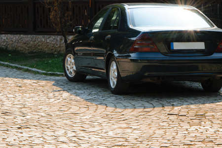 New modern car parked in front of the house, space for text. The sunlight illuminates the back...