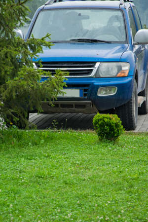 Front view of a parked road vehicle in front of green lawn in front of house, concept of well-being...