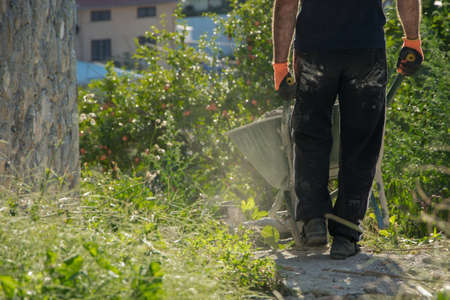 Crop view of young man (worker) with wheelbarrowの写真素材