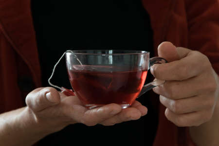 Crop view of woman holding a cup of hot red tea, white background with space for textの写真素材