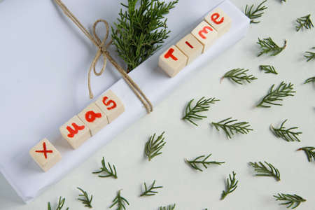 Top view of white handcraft gift box with "X mas time" text (wooden letters) and fresh fir branches on white background, seasonal celebration and eco-friendly conceptの写真素材