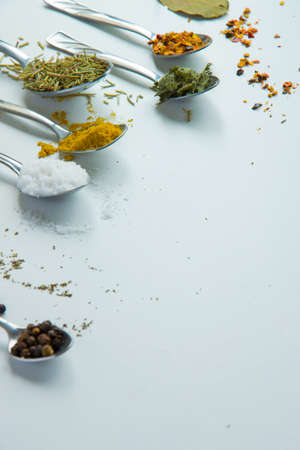 Spoons with various aromatic herbs and spices on white background, space for text. Different...