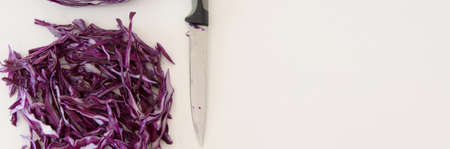 Top view of red sliced cabbage and a knife on white background. Healthy eating concept with space for textの写真素材