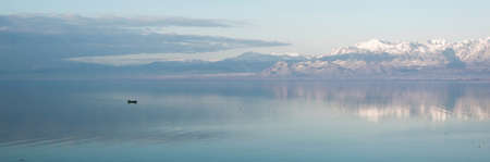 Beautiful scenic landscape  of Shkodra lake, mountains reflection and a little fishing boatの写真素材